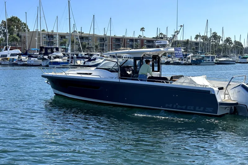 Mdr #187 In Stock Yacht Photos Pics 2023 Nimbus T11 boat cruising in a marina with sailboats and buildings in the background.