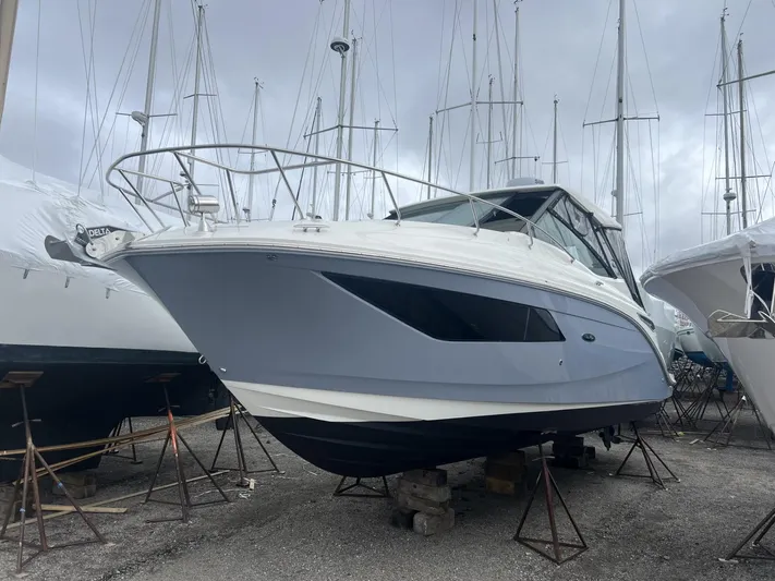  Yacht Photos Pics 2023 Sea Ray Sundancer 320 boat on stands in a marina, overcast sky.
