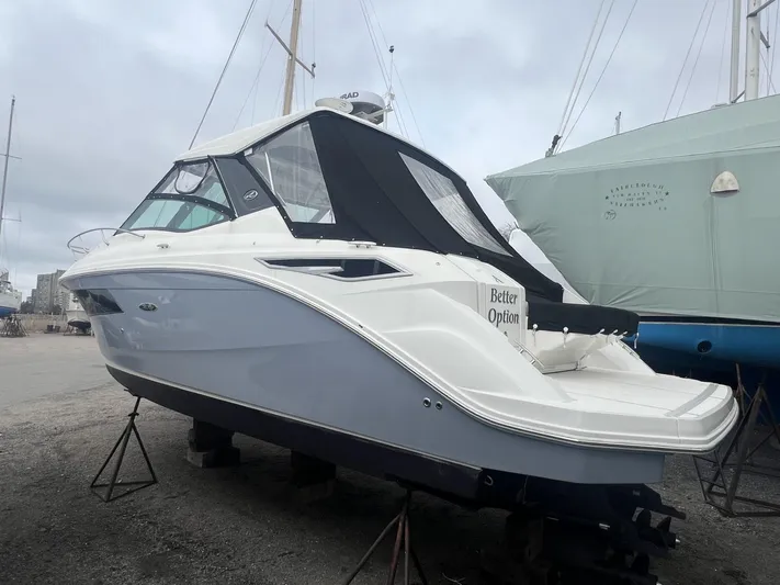  Yacht Photos Pics 2023 Sea Ray Sundancer 320 boat on stands, featuring sleek design and black canopy.