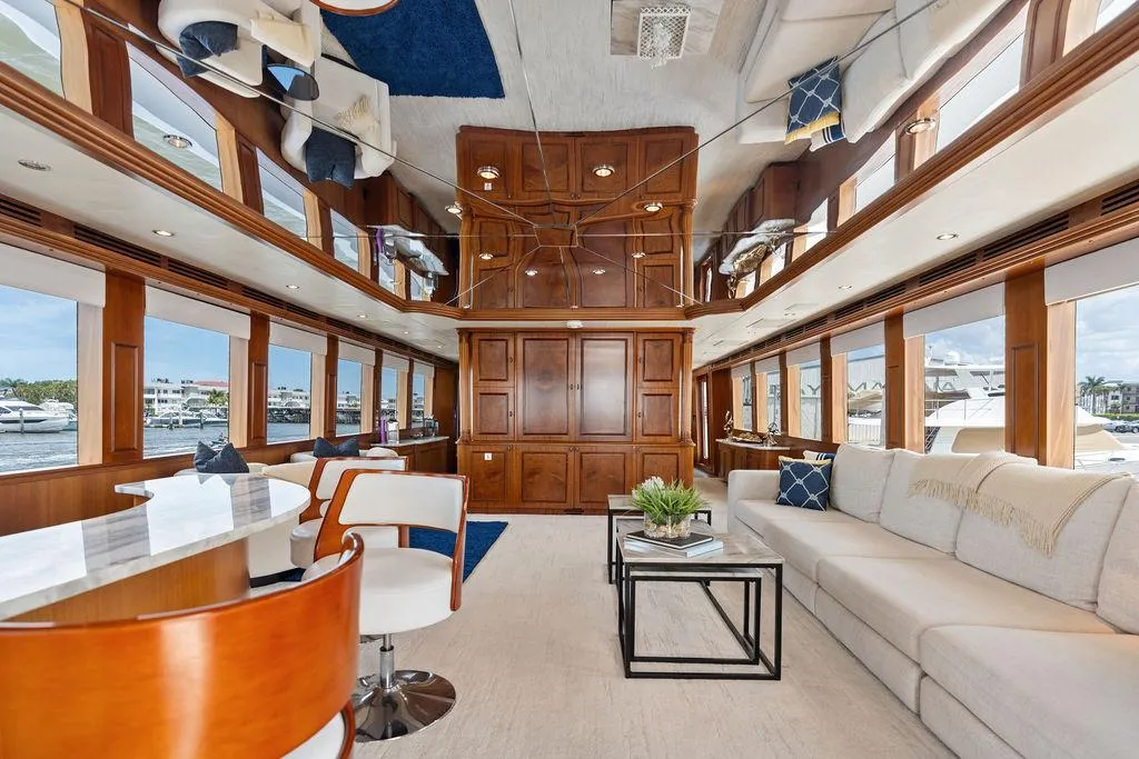 Luxurious interior of 2004 Hatteras 100 Motor Yacht with elegant wood paneling and plush seating.