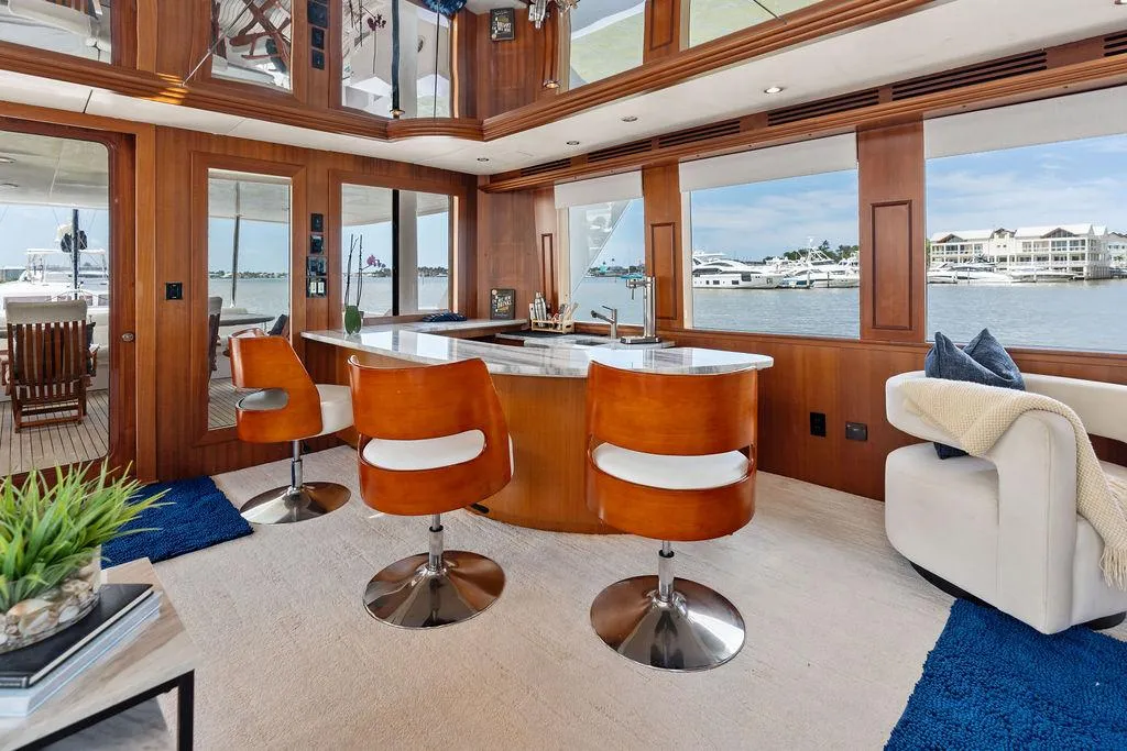 Luxurious interior of 2004 Hatteras 100 Motor Yacht with bar and scenic windows.