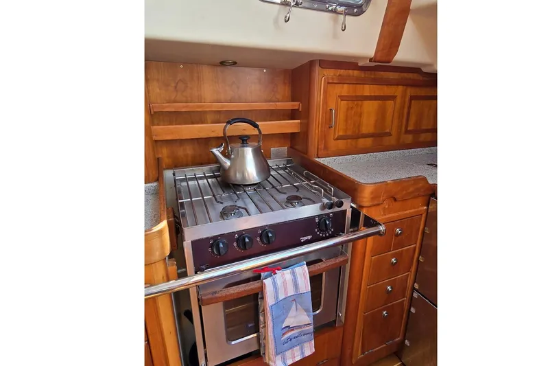 No Se Yacht Photos Pics Compact kitchen in 2004 Saga 43CLS yacht with stove, kettle, and wooden cabinetry.