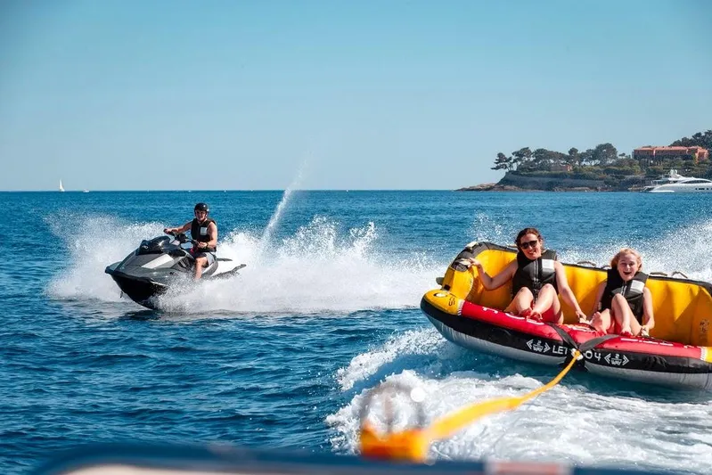 Infinity Nine Yacht Photos Pics Jet ski towing inflatable raft with people enjoying water sports near AvA Yachts Kando 2022.