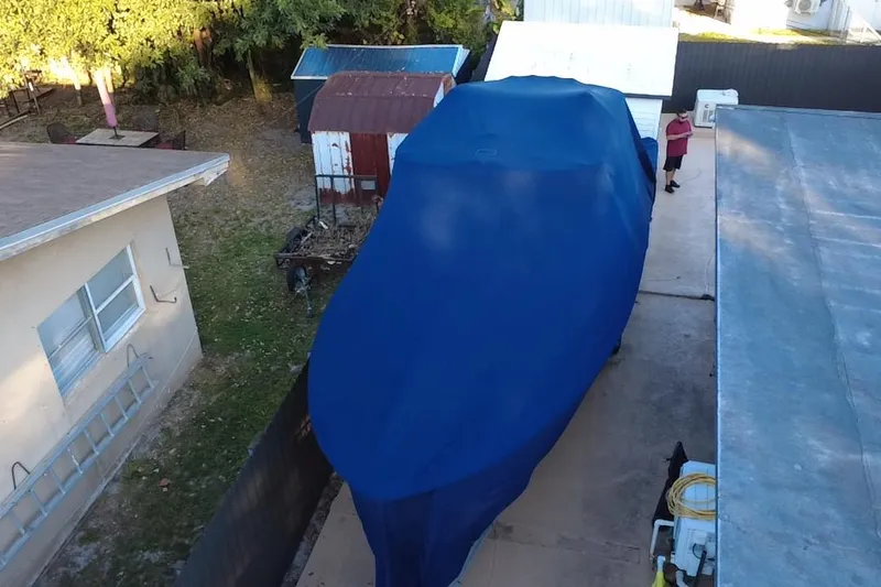  Yacht Photos Pics Covered 2007 Grady-White Bimini 306 boat in driveway, surrounded by buildings and trees.