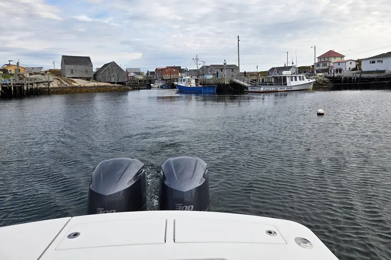  Yacht Photos Pics 2015 Regulator 28 Forward Seating boat in a scenic harbor with coastal buildings.