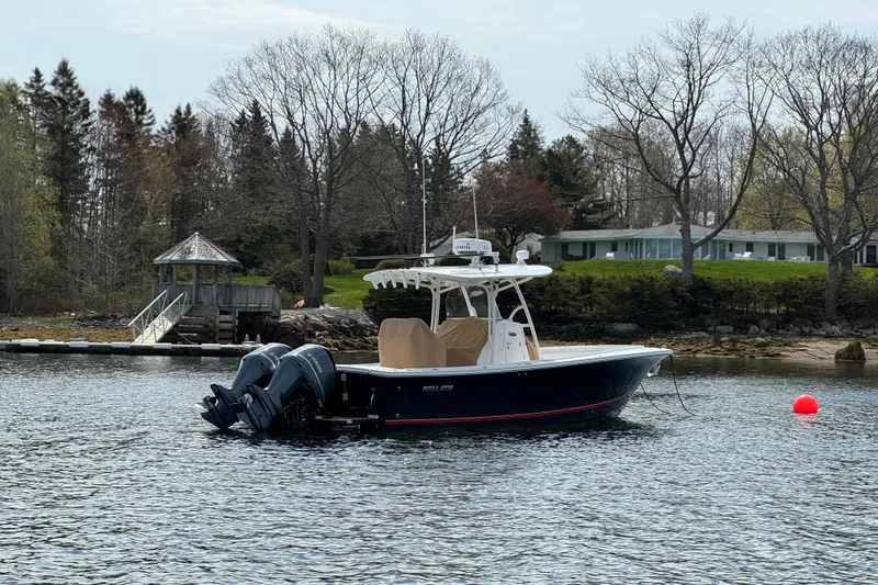  Yacht Photos Pics 2015 Regulator 28 Forward Seating boat on calm water near a dock and trees.