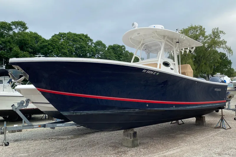  Yacht Photos Pics 2015 Regulator 28 Forward Seating boat on trailer, dark blue hull, red stripe, parked outdoors.