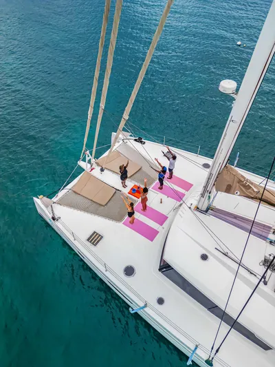 Wonderlust Yacht Photos Pics People doing yoga on a 2016 Fountaine Pajot 72 catamaran in clear blue water.