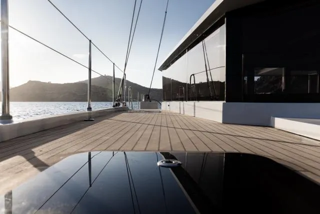  Yacht Photos Pics Modern yacht deck with sleek design, Eyecat 55 Autumn 2024, overlooking serene waters and distant hills.