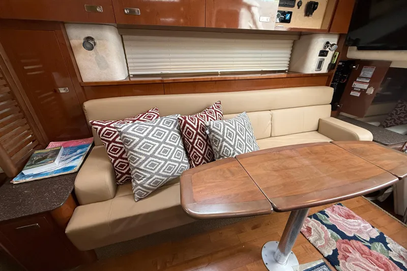  Yacht Photos Pics Interior of 2012 Sea Ray 370 Sundancer with beige sofa, patterned pillows, and wooden table.