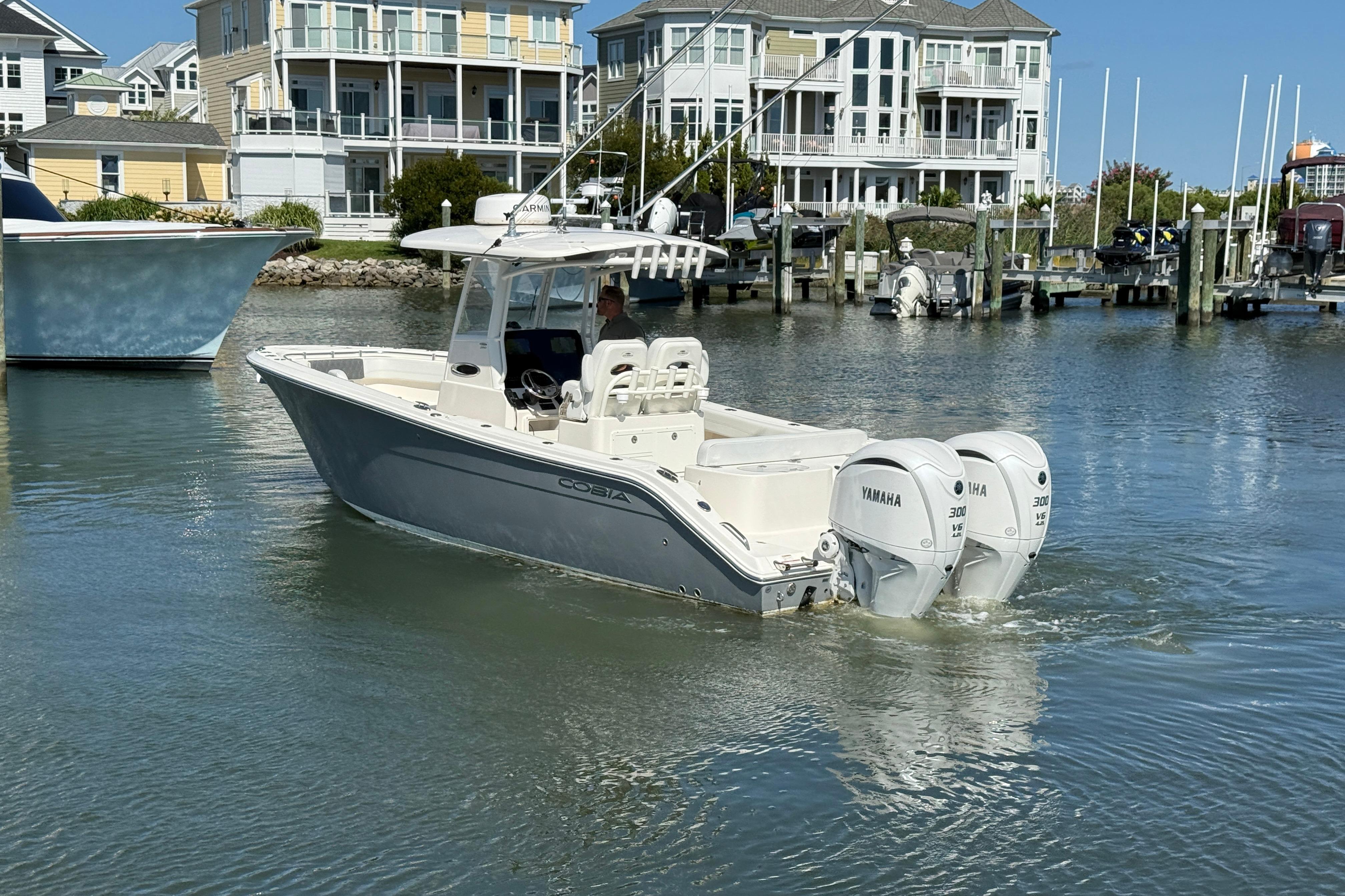 2023 Cobia 280 Center Console boat with twin Yamaha engines in a marina setting.