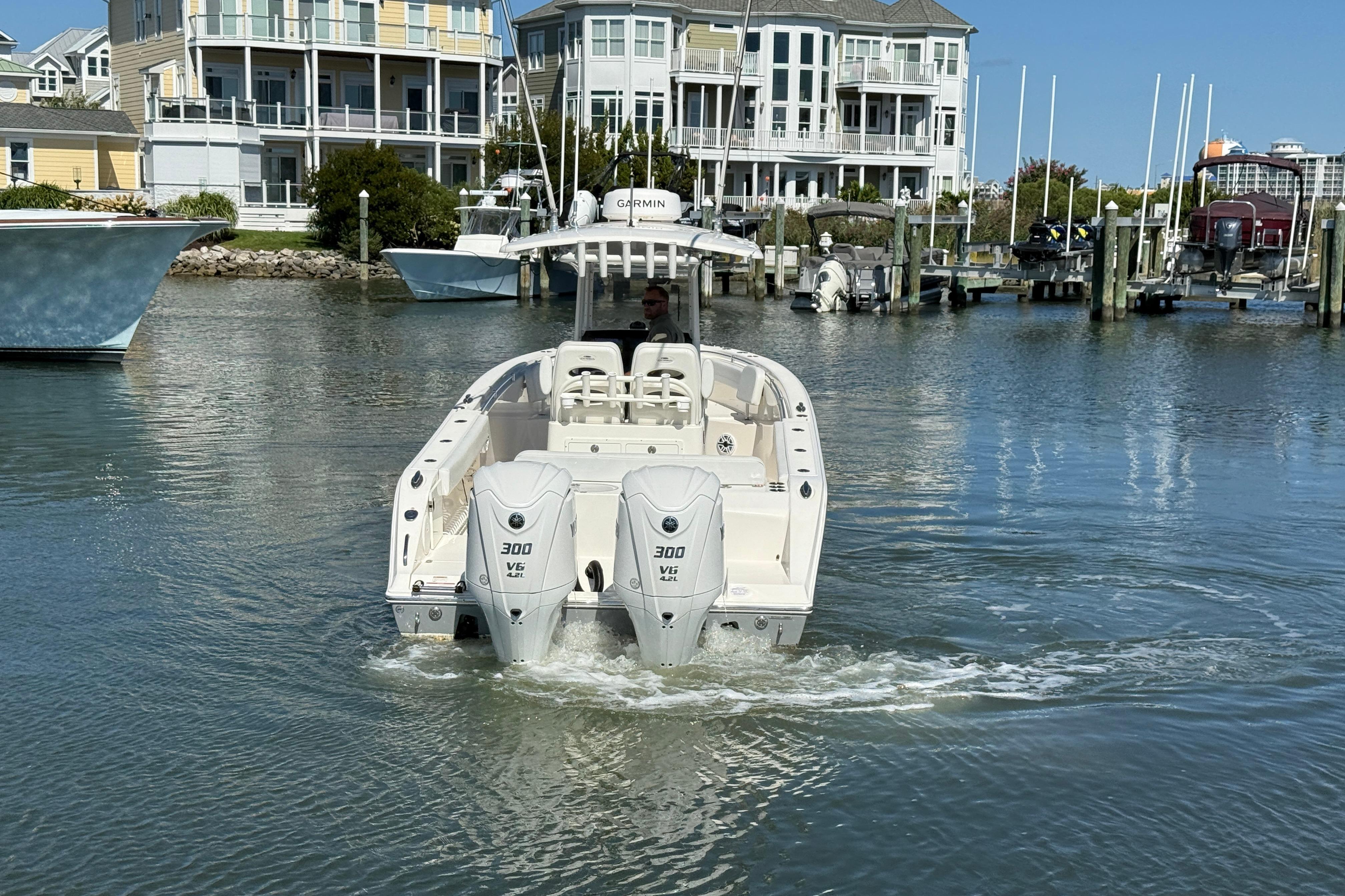 2023 Cobia 280 Center Console boat with twin engines in a marina setting.