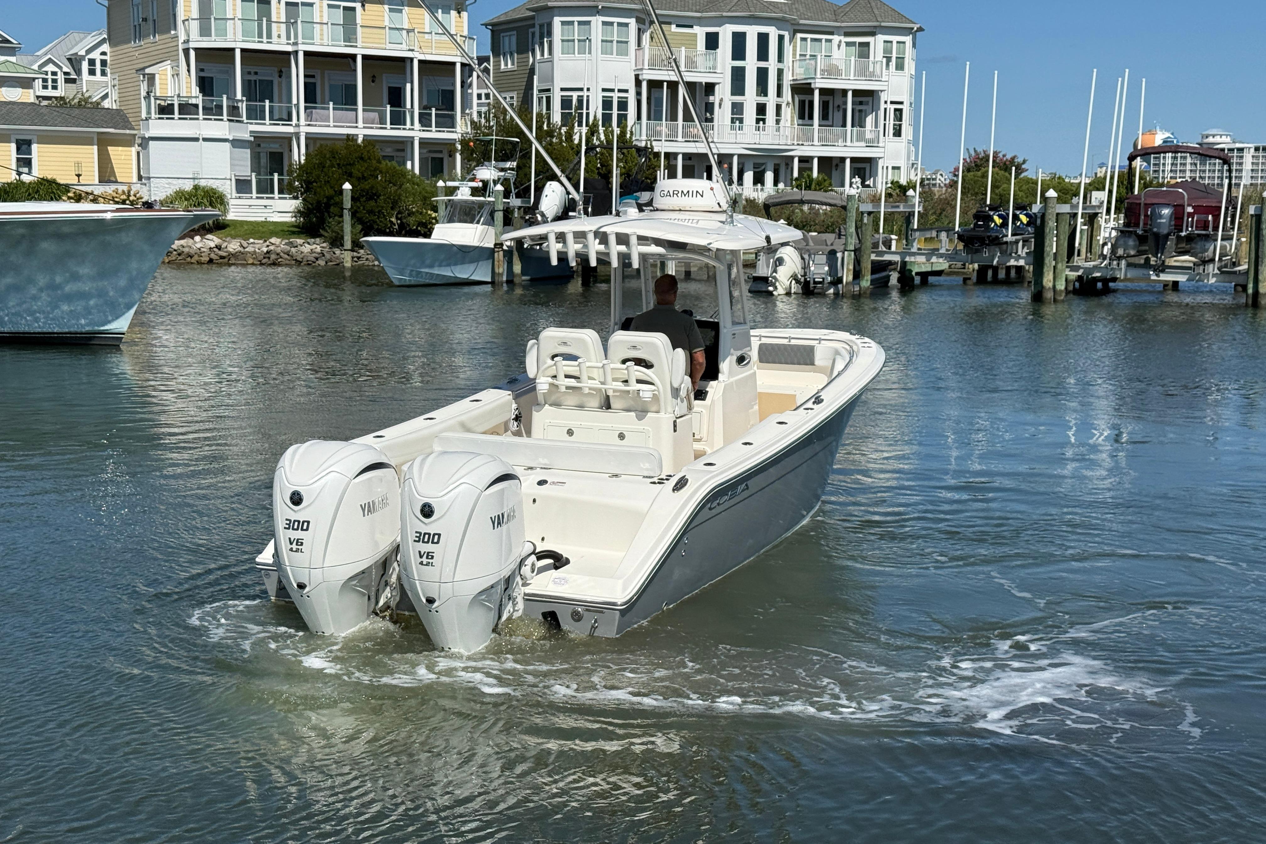 2023 Cobia 280 Center Console boat with twin Yamaha engines in a marina setting.