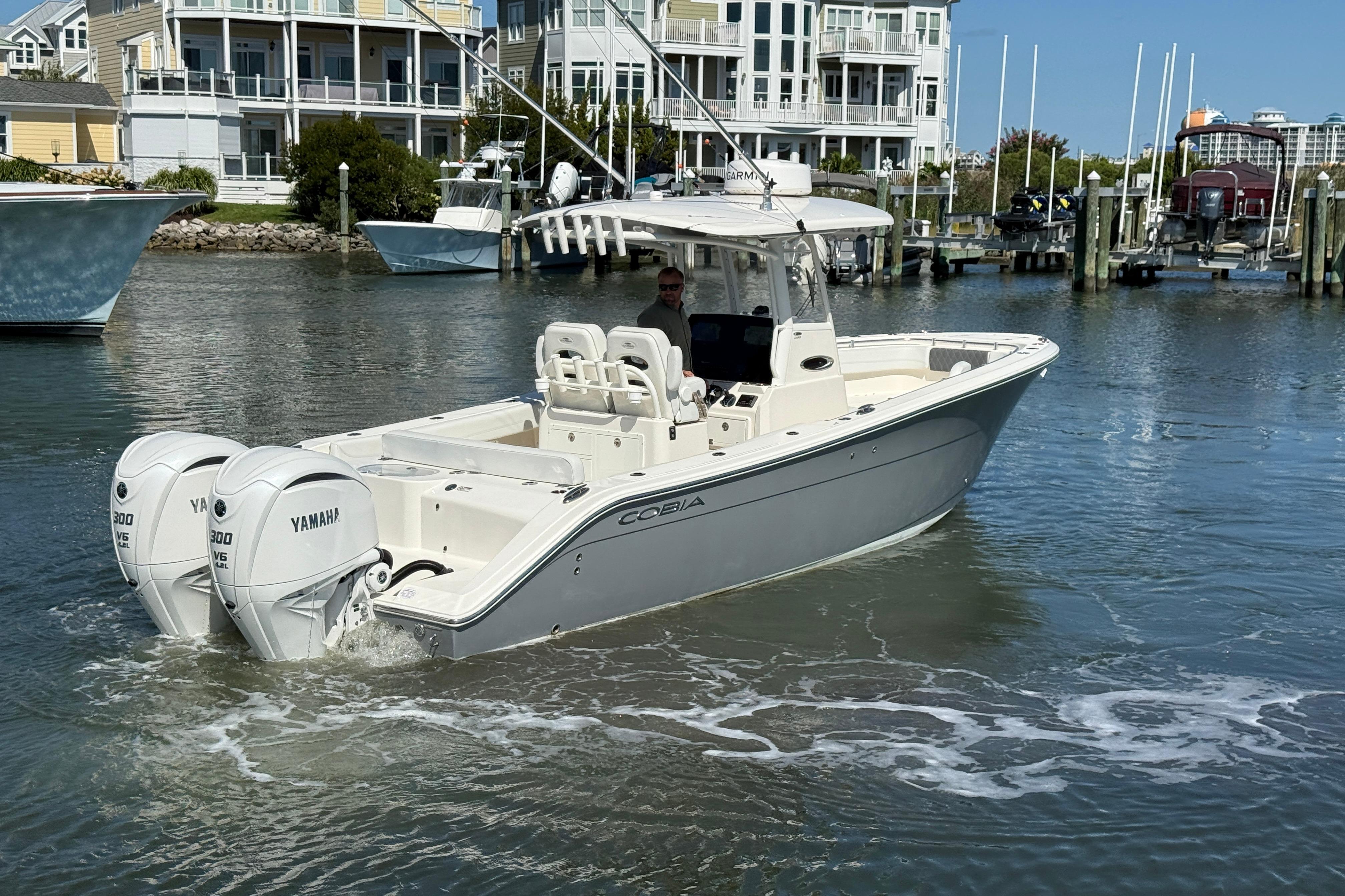 2023 Cobia 280 Center Console boat with twin Yamaha engines in a marina setting.