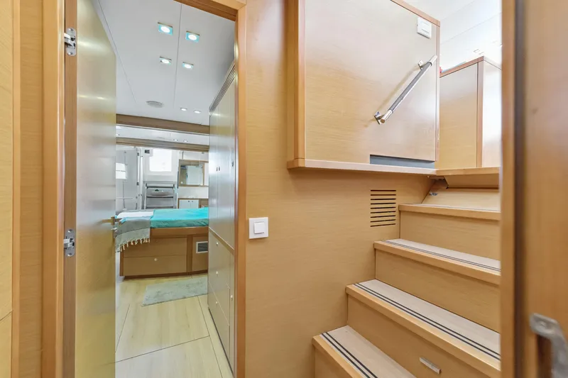 Worth The Wait Yacht Photos Pics Interior of 2012 Lagoon 560 yacht, featuring wooden stairs and a cozy bedroom.