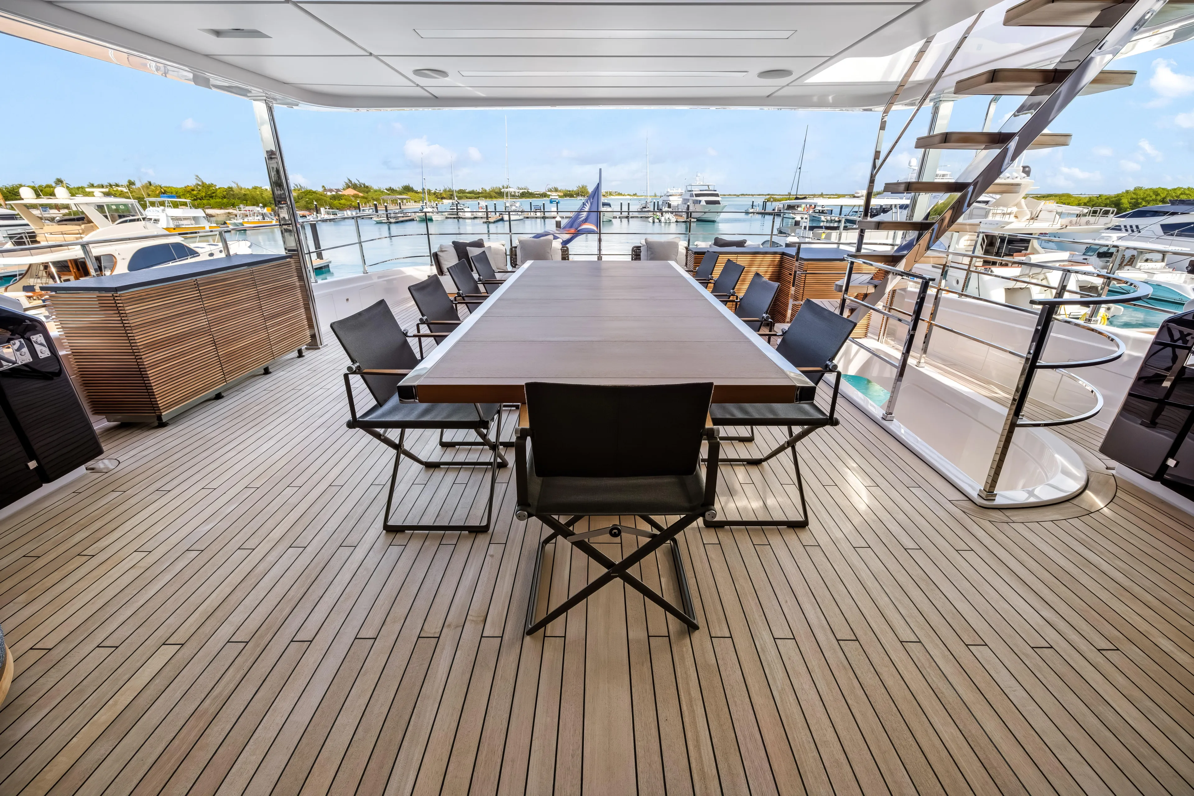 Navetta Yacht Photos Pics Luxurious 2023 Custom Line NAVETTA 42 yacht deck with elegant dining area and marina view.