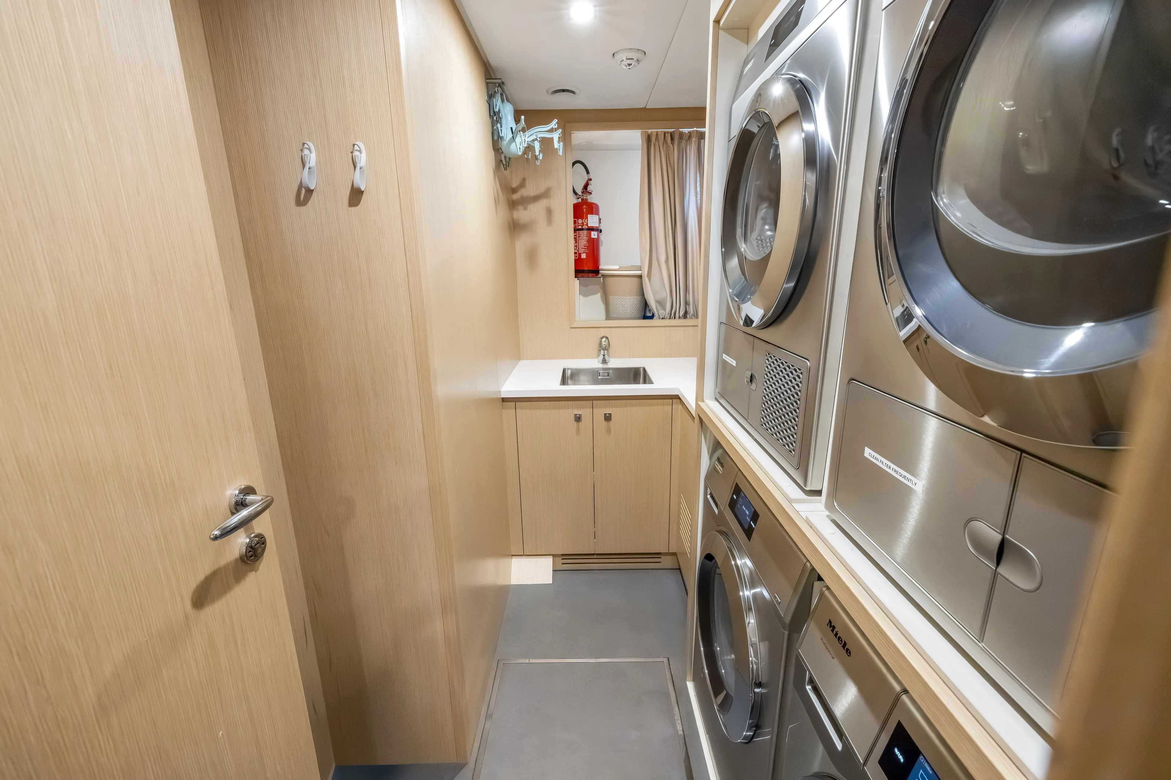 Navetta Yacht Photos Pics Laundry room on 2023 Custom Line NAVETTA 42 yacht with modern appliances and wooden cabinetry.