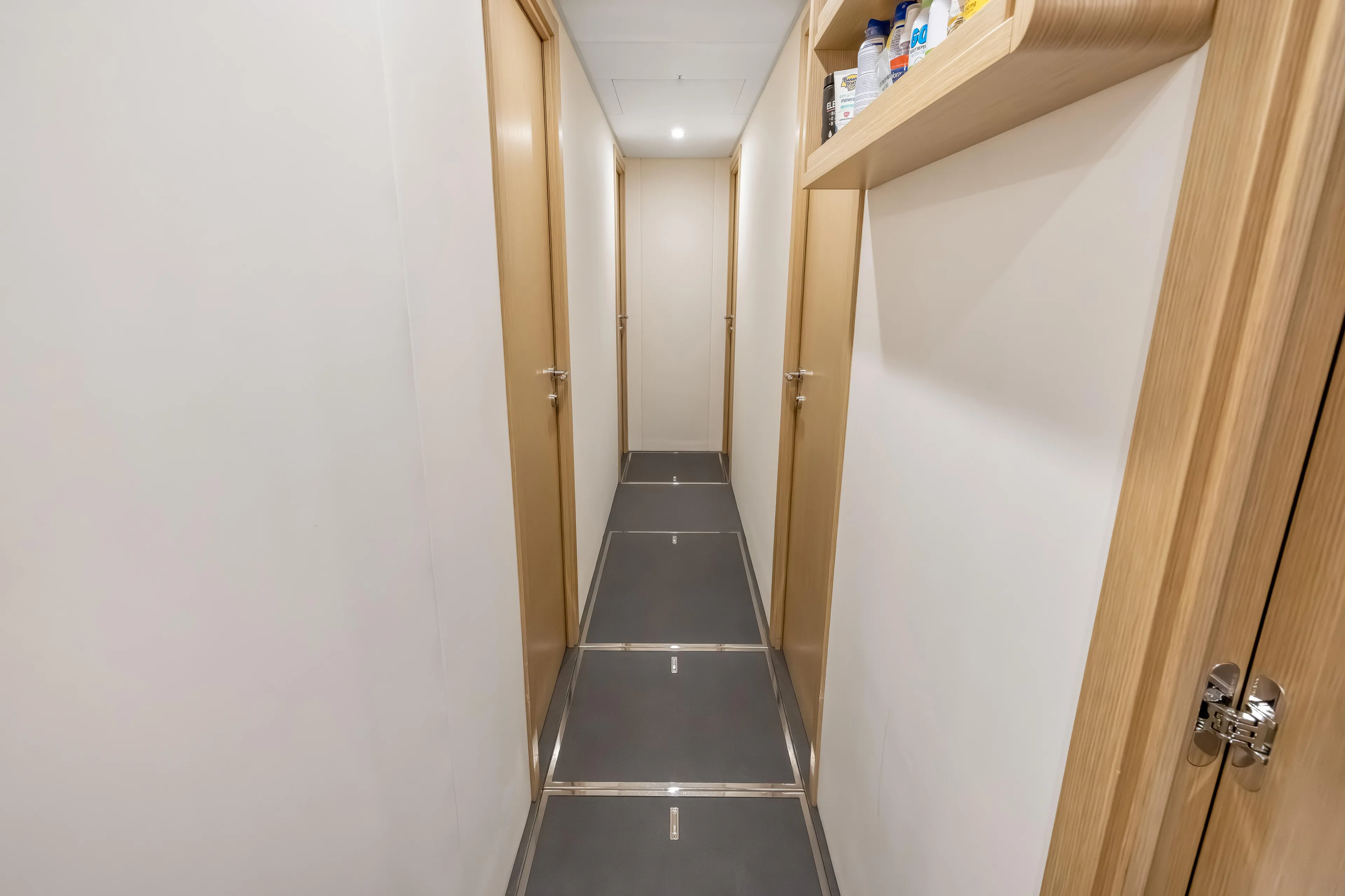 Navetta Yacht Photos Pics Narrow hallway inside 2023 Custom Line NAVETTA 42 yacht, featuring wooden doors and shelving.