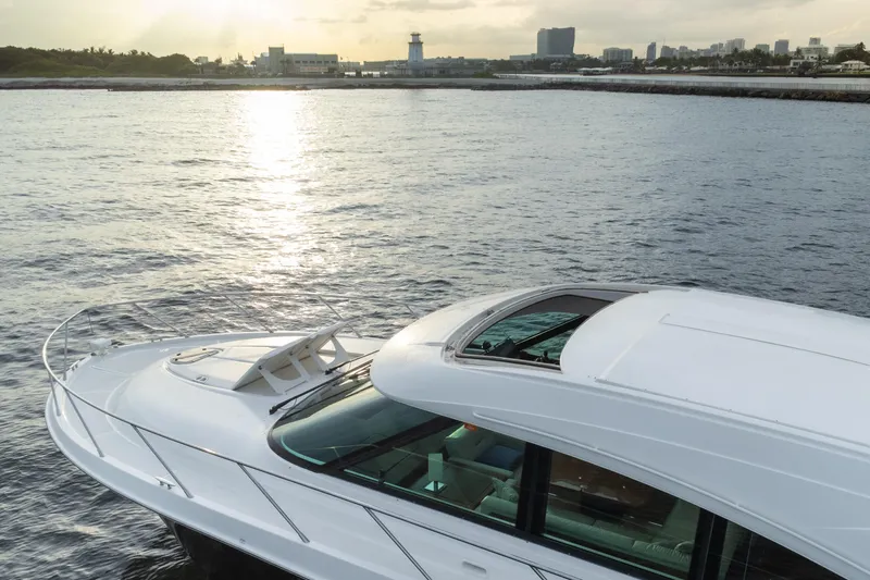 Happy Daze IV Yacht Photos Pics 2017 Tiara Yachts C53 Coupe on serene water with cityscape and lighthouse in background.