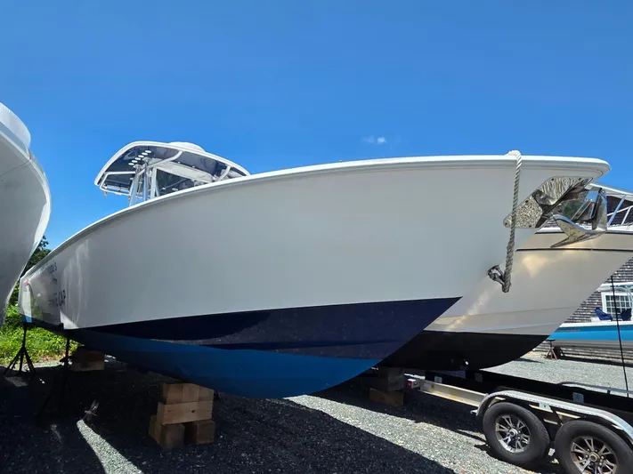 White Cap Yacht Photos Pics 2016 Contender 32 ST boat on display, resting on wooden blocks, under clear blue sky.
