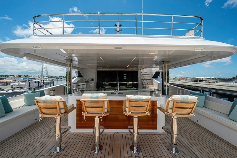 Checked Out Yacht Photos Pics Luxury Majesty 140 yacht deck with bar stools, 2020 model, under clear blue sky.
