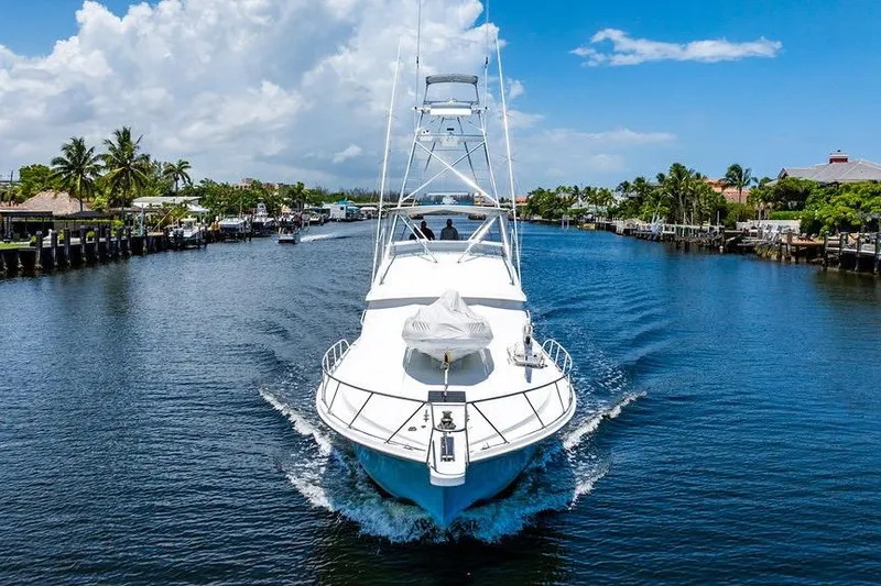 Energy Yacht Photos Pics 1998 Bertram 60 Convertible yacht cruising on a scenic waterway under a clear blue sky.