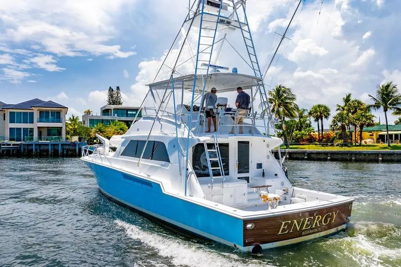 Energy Yacht Photos Pics 1998 Bertram 60 Convertible yacht cruising near waterfront homes under a sunny sky.