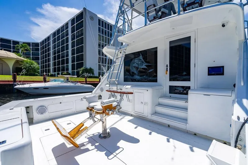 Energy Yacht Photos Pics 1998 Bertram 60 Convertible yacht deck with fishing chair, docked near modern buildings.