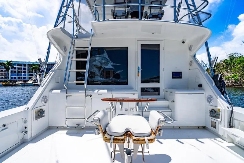 Energy Yacht Photos Pics 1998 Bertram 60 Convertible yacht deck with fishing chair and ladder, docked by waterfront buildings.