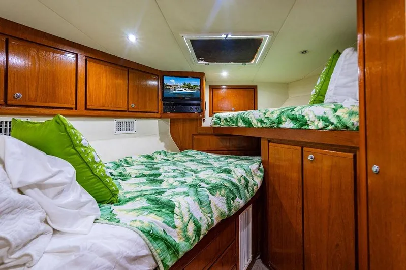 Energy Yacht Photos Pics Cozy cabin interior of 1998 Bertram 60 Convertible with wooden cabinets and tropical bedding.