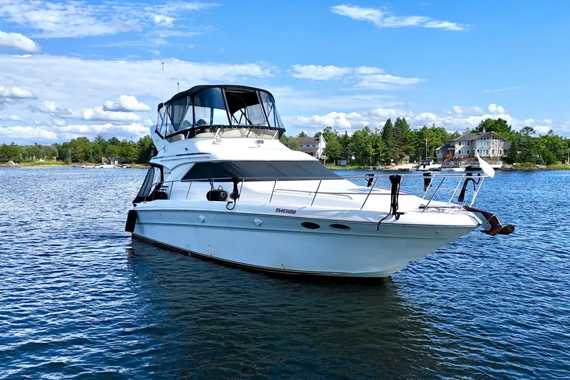 Shaneanigans Yacht Photos Pics 1998 Sea Ray 400 Sedan Bridge yacht on serene lake with blue sky backdrop.
