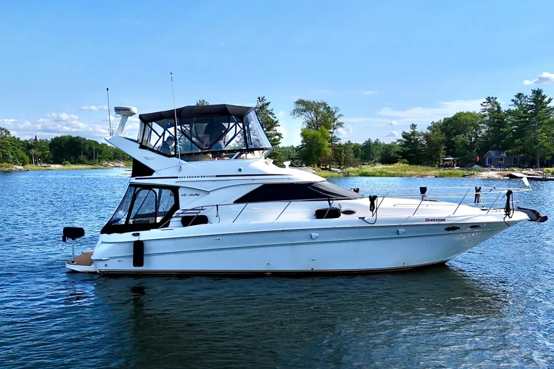 Shaneanigans Yacht Photos Pics 1998 Sea Ray 400 Sedan Bridge yacht on a serene lake with lush greenery.
