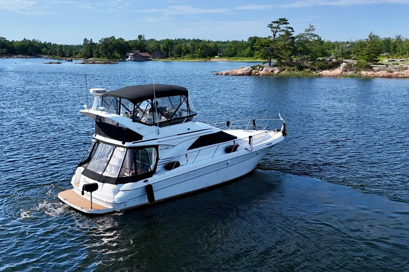 Shaneanigans Yacht Photos Pics 1998 Sea Ray 400 Sedan Bridge yacht cruising on a serene lake.
