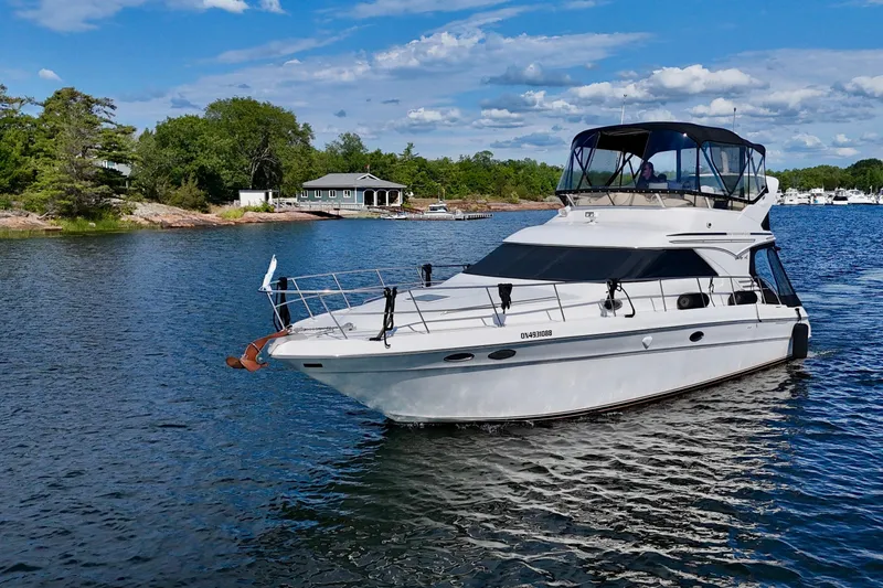 Shaneanigans Yacht Photos Pics 1998 Sea Ray 400 Sedan Bridge yacht cruising on a scenic lake under a clear blue sky.