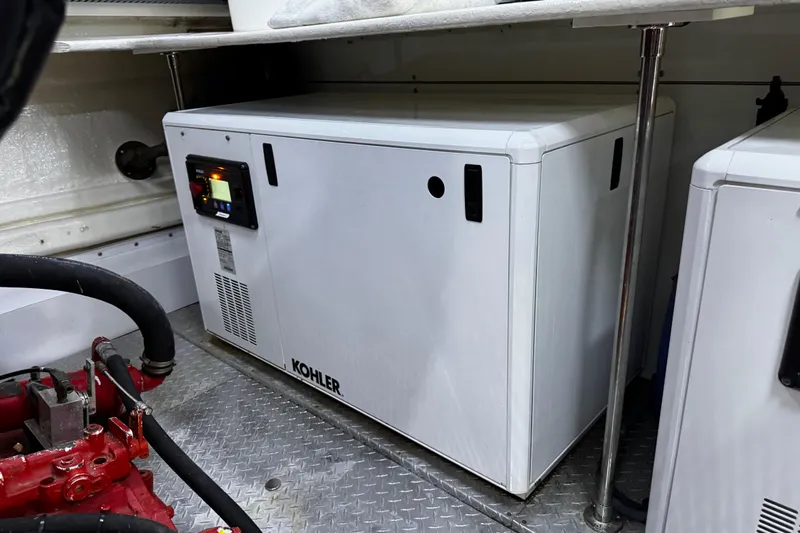 Atlantis Yacht Photos Pics Kohler generator in 1996 Hershine Benship 87 engine room, featuring metal flooring and piping.