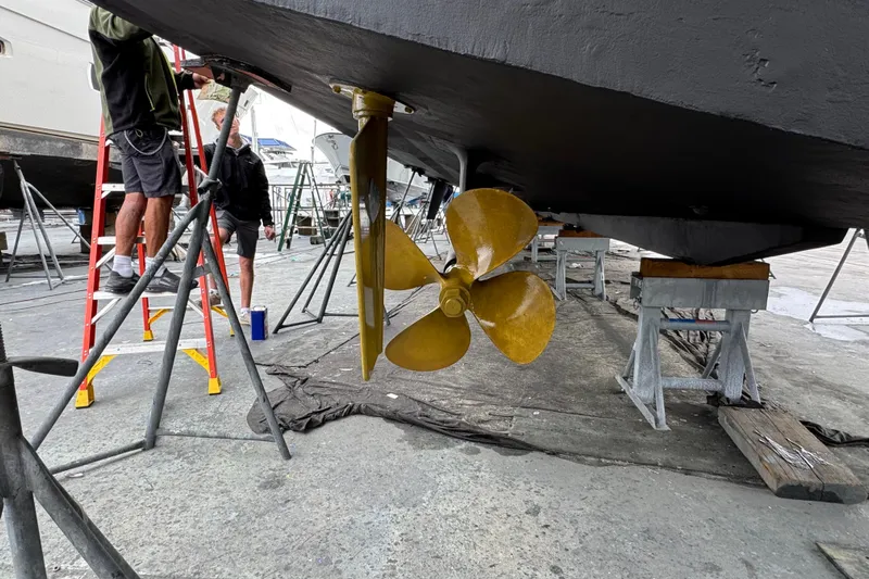 Atlantis Yacht Photos Pics Workers inspecting 1996 Hershine Benship 87 yacht propeller in a shipyard.