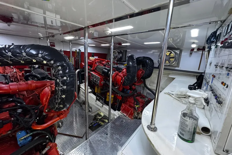 Atlantis Yacht Photos Pics Engine room of 1996 Hershine Benship 87 yacht with red machinery and control panels.