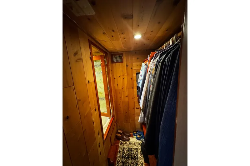 Atlantis Yacht Photos Pics Wood-paneled closet with clothes hanging, inside a 1996 Hershine Benship 87 yacht.