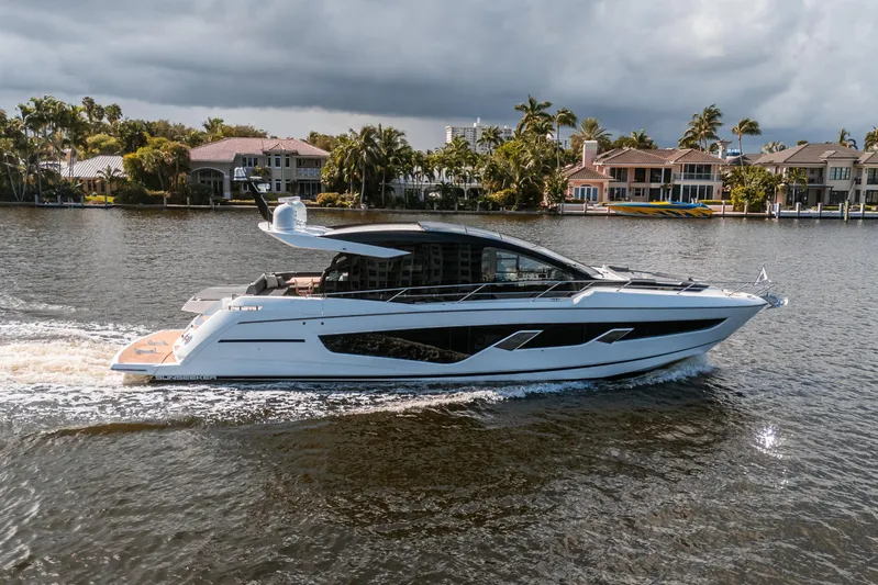 Lorena Yacht Photos Pics 2022 Sunseeker Predator 65 yacht cruising on a scenic waterway near luxury homes.