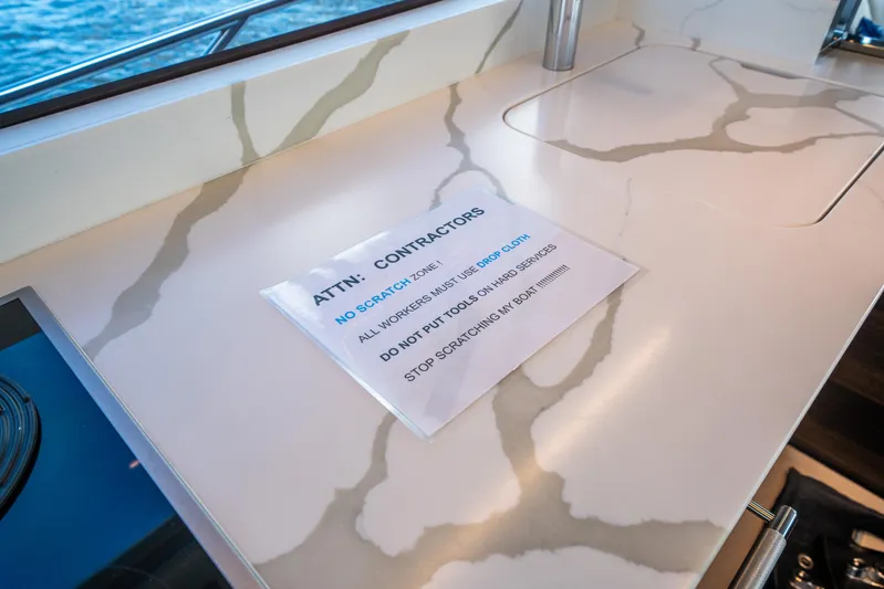 Lorena Yacht Photos Pics Luxury Sunseeker Predator 65 yacht interior with no-scratch zone sign on marble countertop.