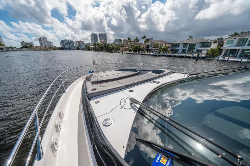 Lorena Yacht Photos Pics 2022 Sunseeker Predator 65 yacht on water, city skyline and clouds reflected on deck.