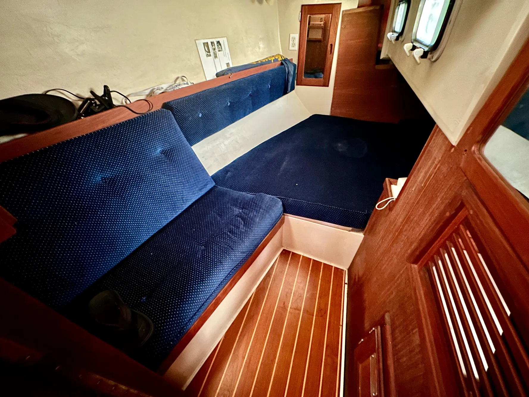 Interior of a 1987 Catalina 34 with blue cushions and wooden flooring.