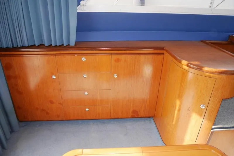  Yacht Photos Pics Interior of 1994 Fairline Phantom 37 yacht with wooden cabinetry and blue curtains.