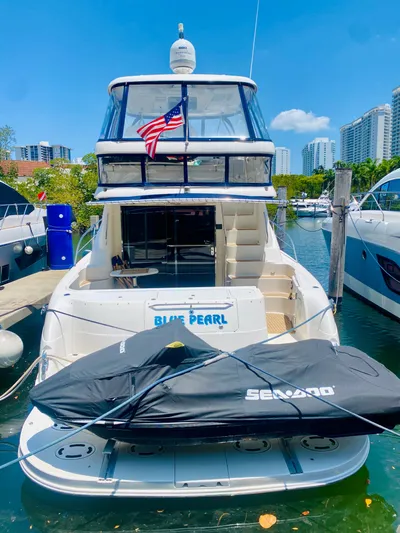 Blue Pearl Yacht Photos Pics 2006 Sea Ray 580 Sedan Bridge yacht docked with jet ski, city skyline in background.