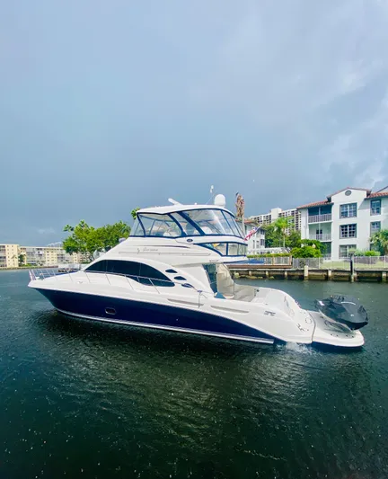 Blue Pearl Yacht Photos Pics 2006 Sea Ray 580 Sedan Bridge yacht on calm water near waterfront buildings.