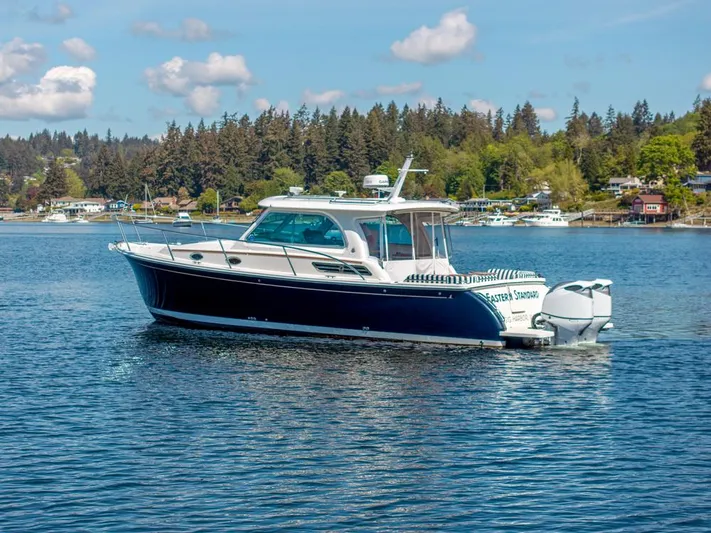Eastern Standard Yacht Photos Pics 2021 Back Cove 34O boat cruising on a scenic lake with forested shoreline.