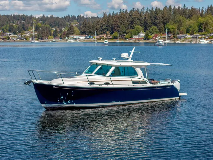 Eastern Standard Yacht Photos Pics 2021 Back Cove 34O boat on a serene lake with forested shoreline.