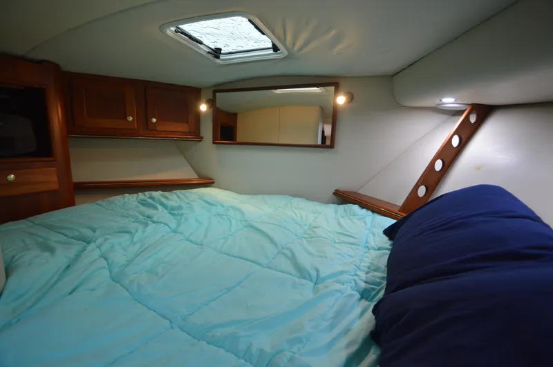 Side Chick Yacht Photos Pics Cozy cabin interior of 2002 Rampage 38 Express with blue bedding and wooden accents.