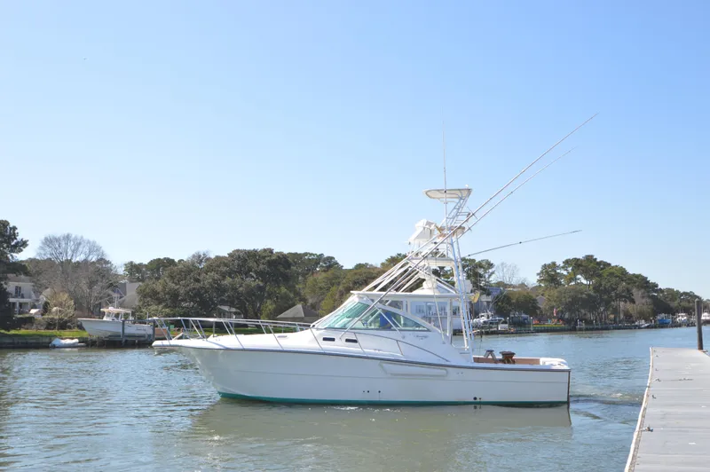 Side Chick Yacht Photos Pics 2002 Rampage 38 Express boat cruising on a calm river near a dock.