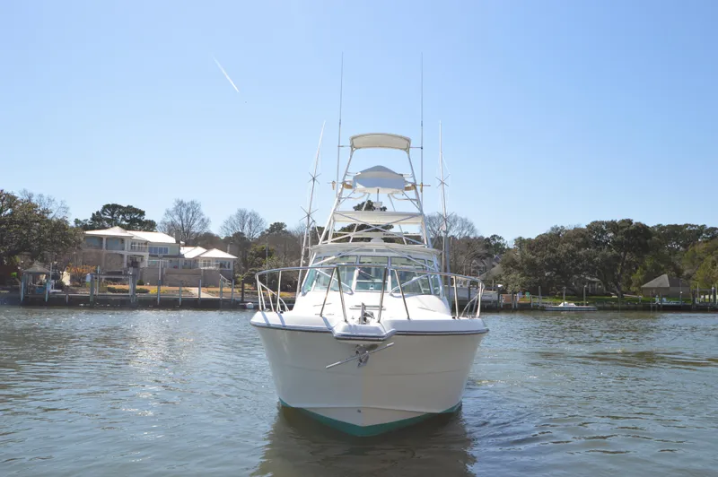 Side Chick Yacht Photos Pics 2002 Rampage 38 Express boat on calm water, with houses and trees in the background.